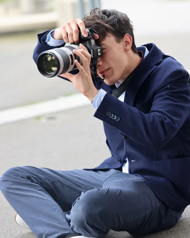 David Schinzel fotografiert im Sitzen mit Teleobjektiv